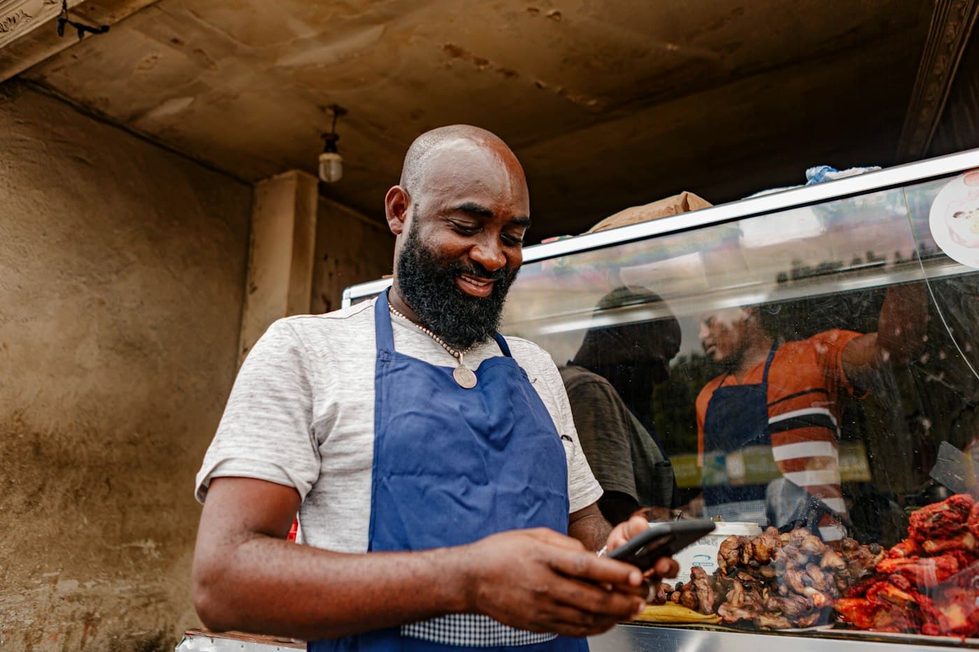 A food stall owner smiling at a customer message on his phone